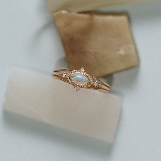Marquise-cut iridescent opal ring in gold with a triple-band design and north star accents, ethereal celestial jewelry by LIRAE.