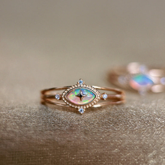 Marquise-cut iridescent opal ring in 14k gold with a triple-band design and north star accents, ethereal celestial jewelry by LIRAE.