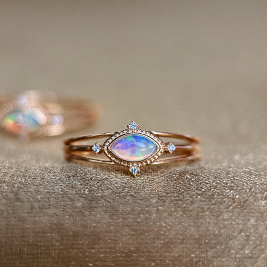 Marquise-cut iridescent opal ring in 14k gold with a triple-band design and north star accents, ethereal celestial jewelry by LIRAE.