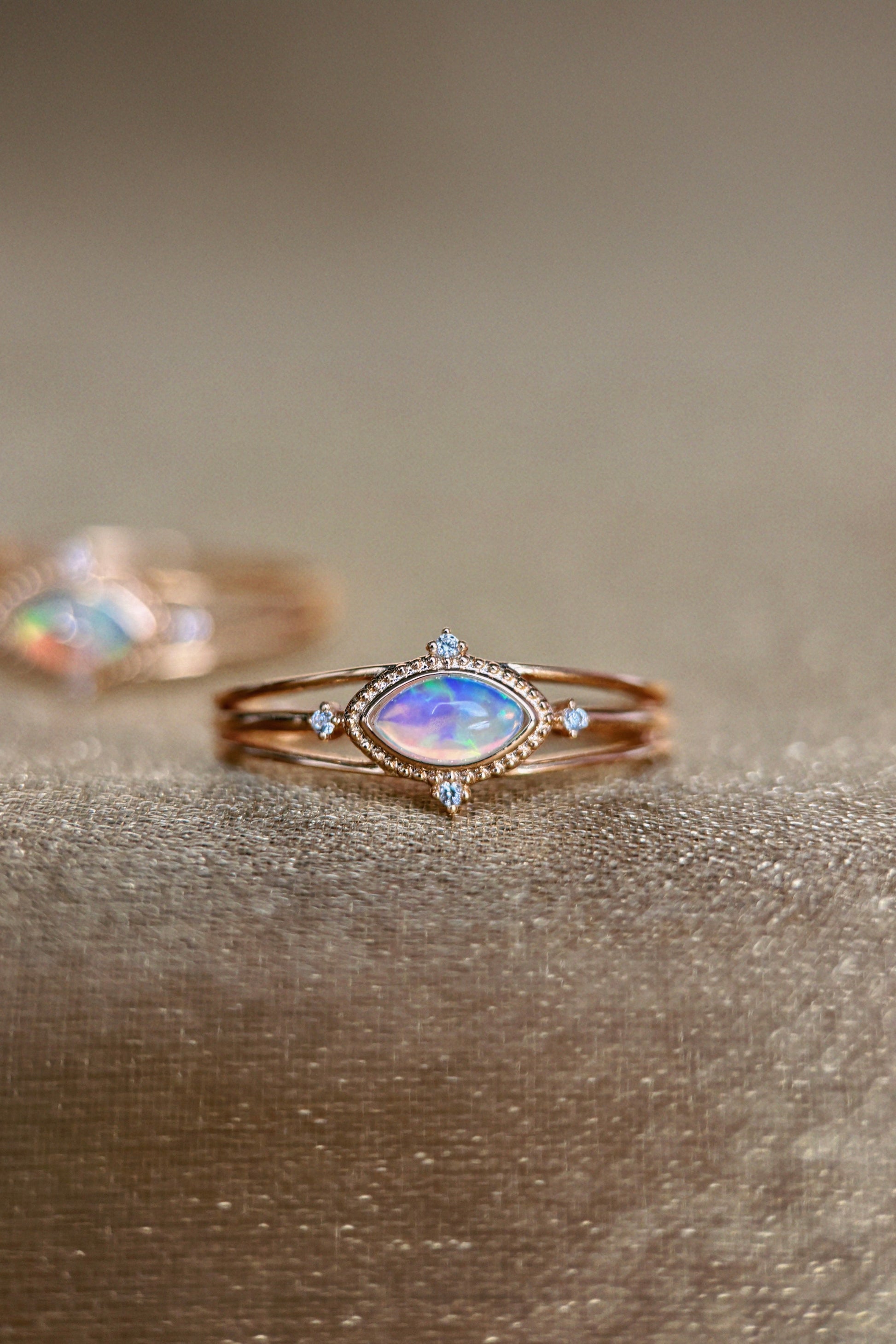 Marquise-cut iridescent opal ring in 14k gold with a triple-band design and north star accents, ethereal celestial jewelry by LIRAE.
