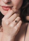 Close-up of a person wearing a gold ring with moss agate.