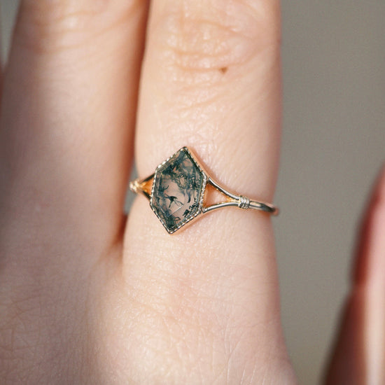 Moss agate ring with green inclusions on delicate gold band.
