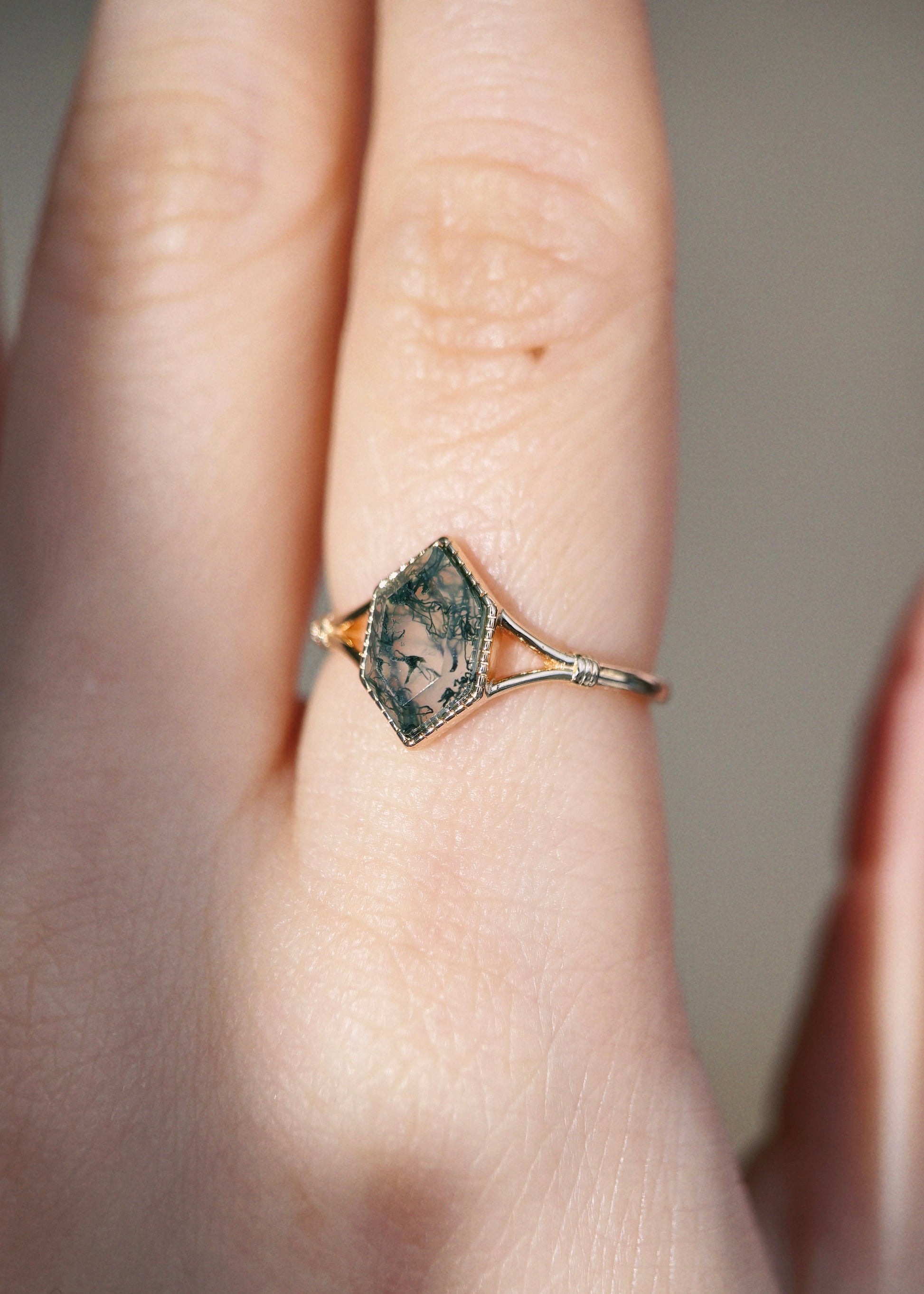 Moss agate ring with green inclusions on delicate gold band.
