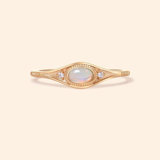 Gold oval opal ring with moissanite accents and vintage-inspired details.