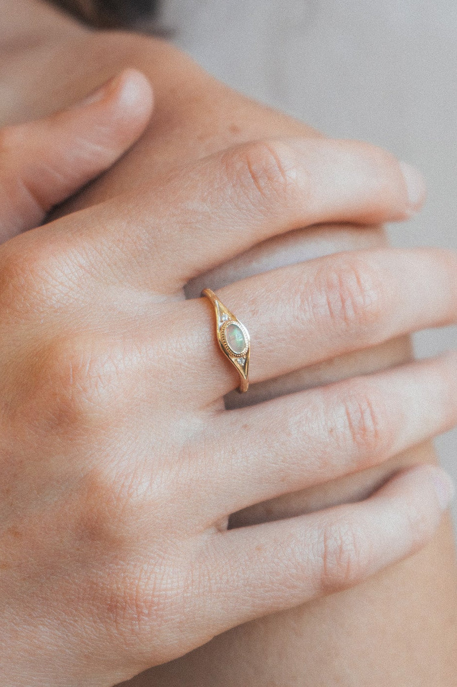 Gold oval opal ring with moissanite accents and vintage-inspired details.