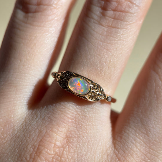 LIRAE vintage-style gold ring with an oval opal center stone and intricate golden swirl filigree, ethereal romantic jewelry for women.