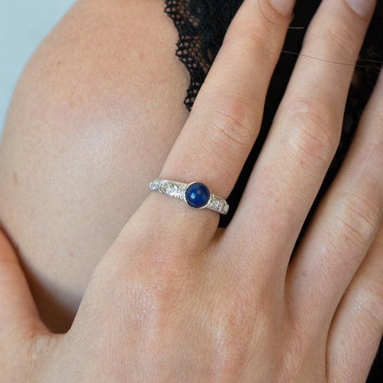 Silver celestial lapis lazuli ring with round blue center stone and engraved moon and star details