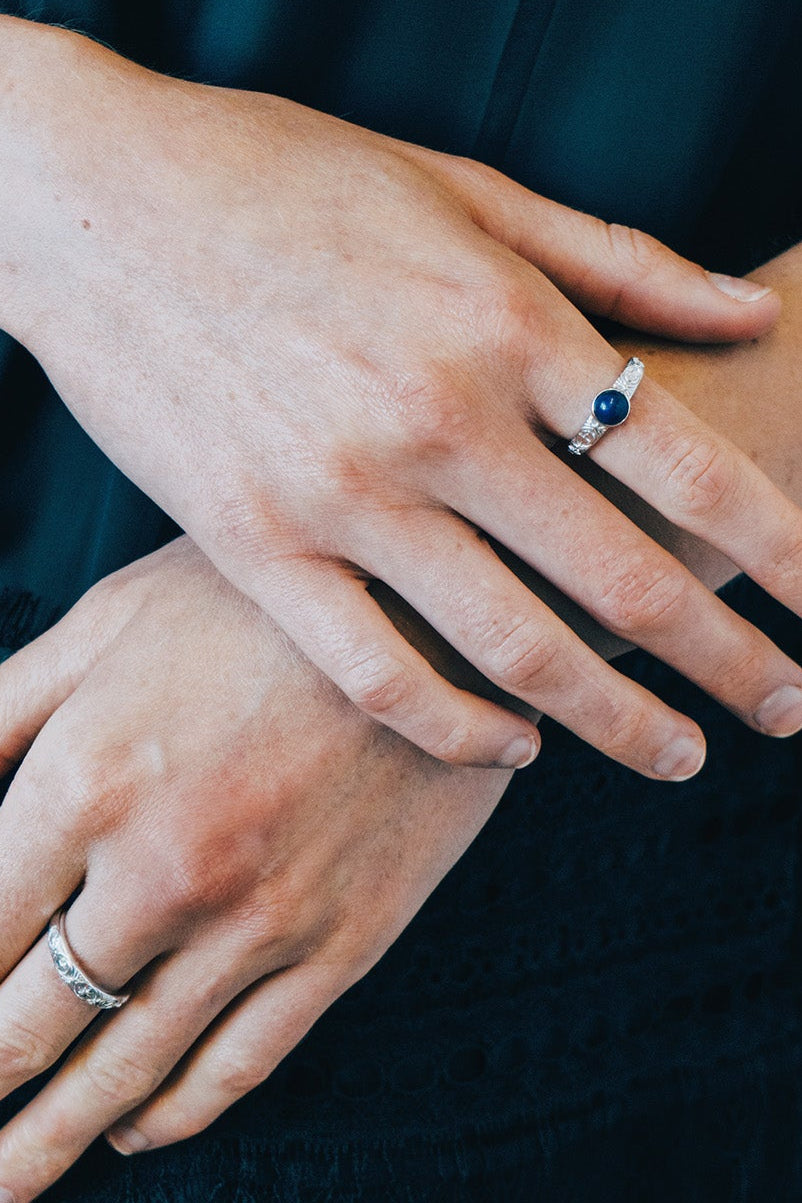 Silver celestial lapis lazuli ring with round blue center stone and engraved moon and star details