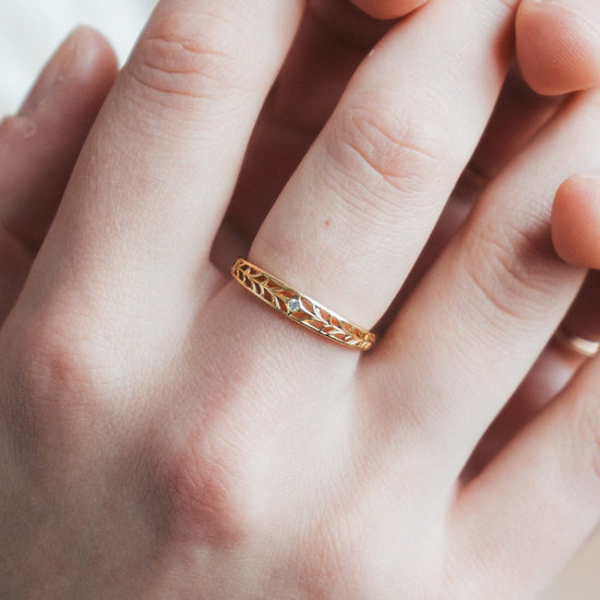 Intricately hollowed gold eternity band with a central starburst diamond, celestial stacking ring by LIRAE.