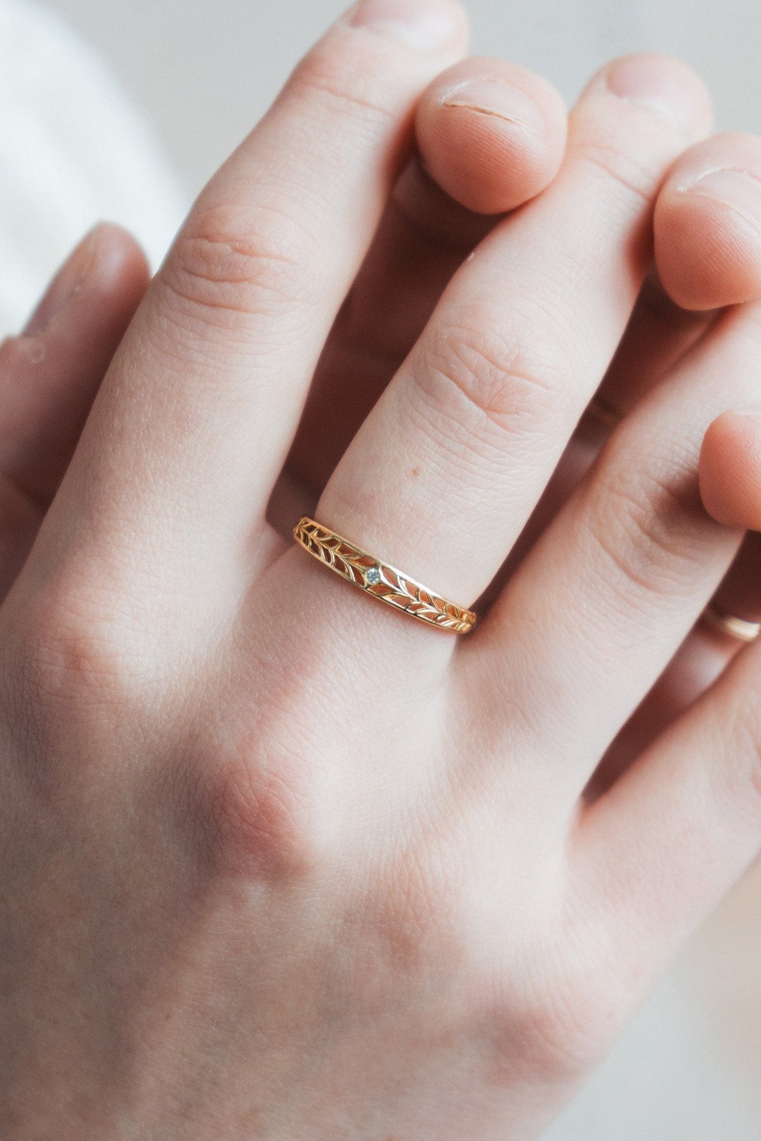 Intricately hollowed gold eternity band with a central starburst diamond, celestial stacking ring by LIRAE.
