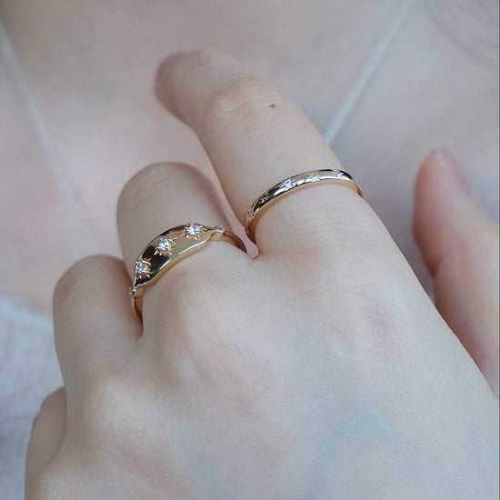 Hand wearing a 14K gold plated ring with starburst engravings, celestial jewelry by Lirae.