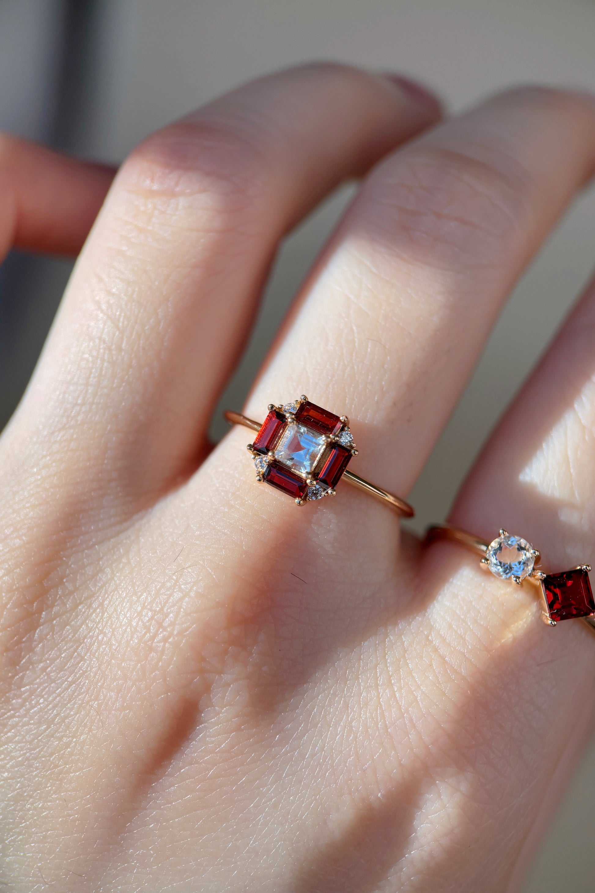 LIRAE vintage Art Deco ring with an octagon halo of red garnet baguettes and a white topaz center stone, geometric gold statement ring for women.