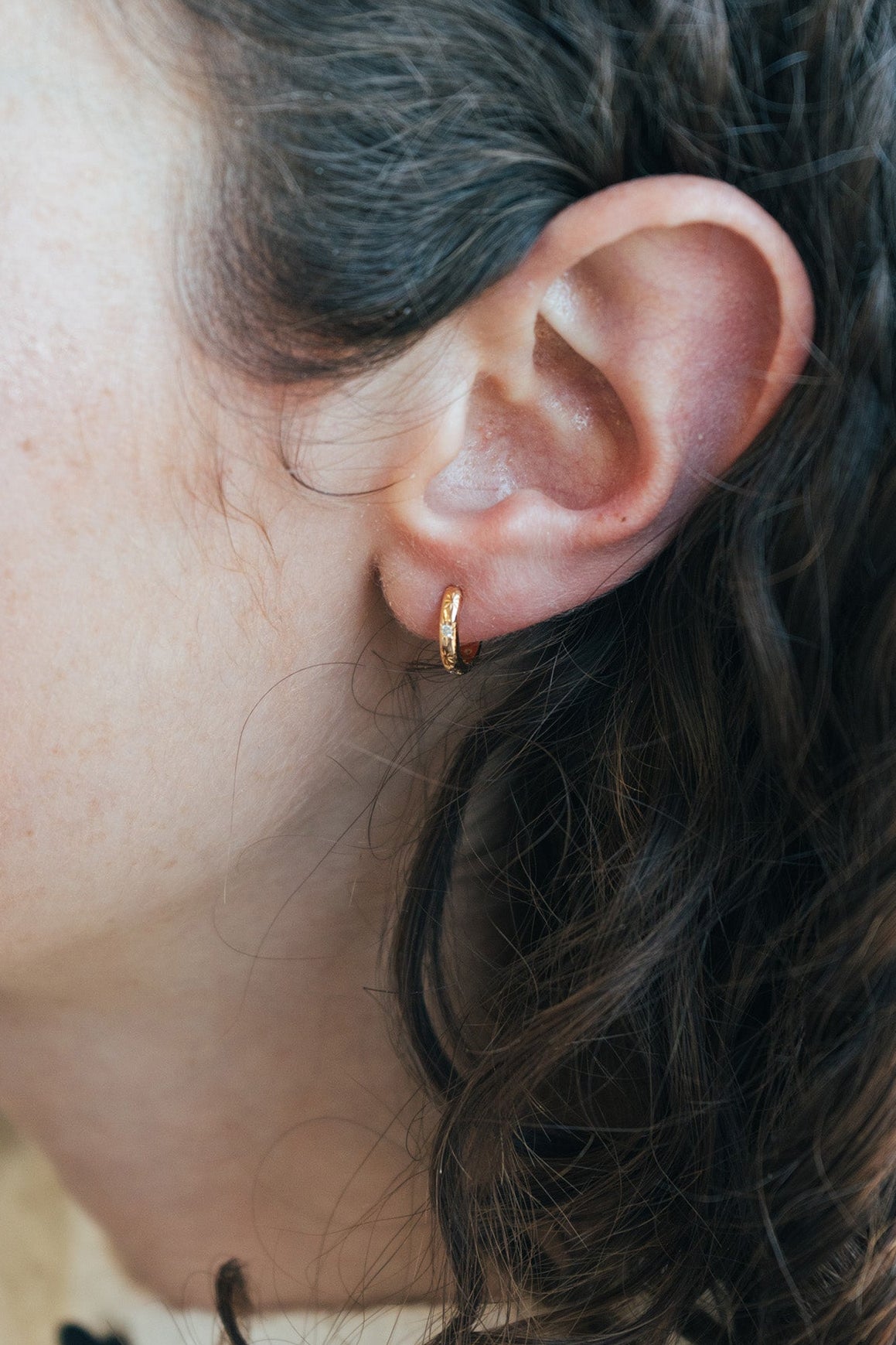 Gold small hoop earrings with engraved star details and moissanites accents