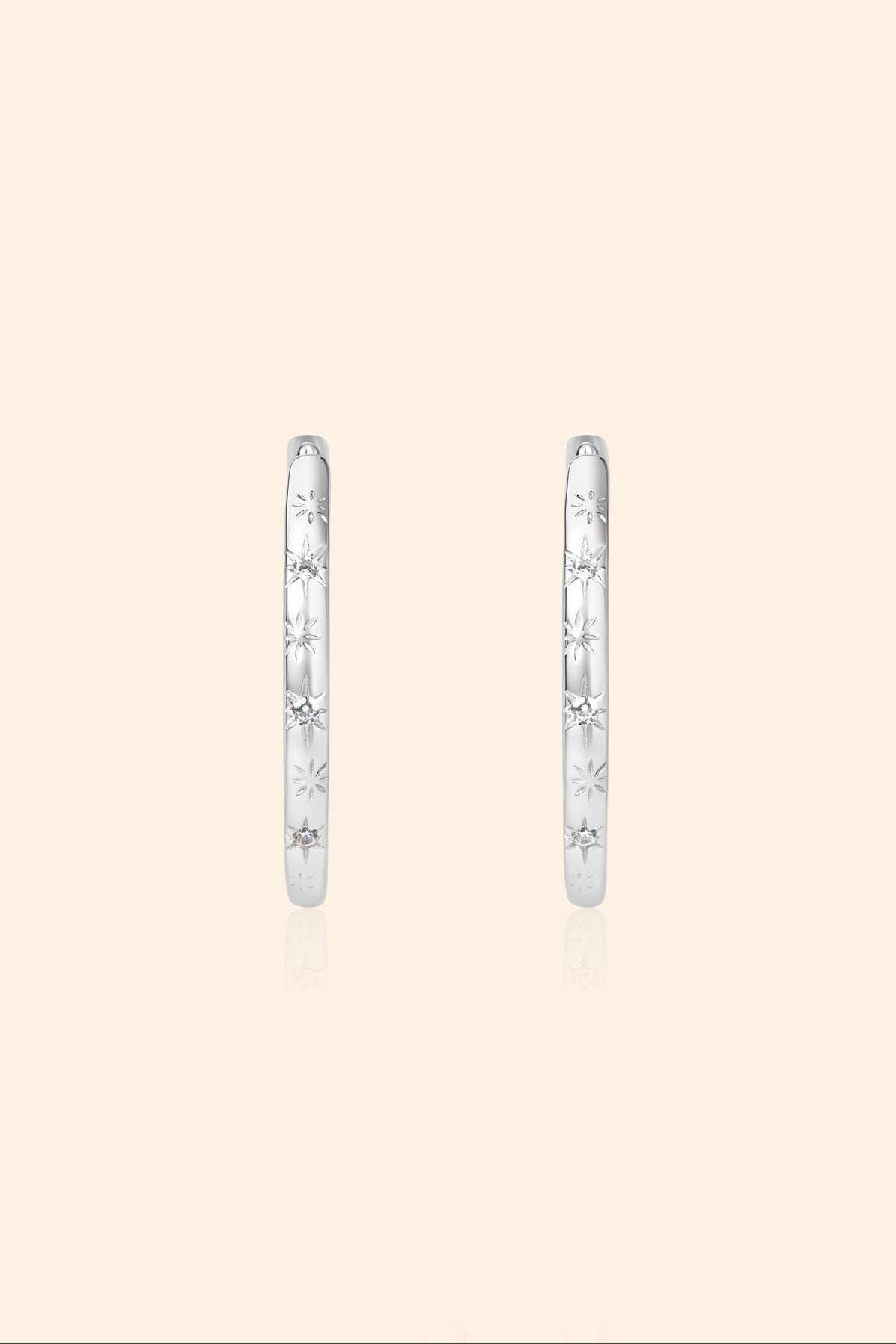 Silver medium hoop earrings with engraved star details and moissanites accents.