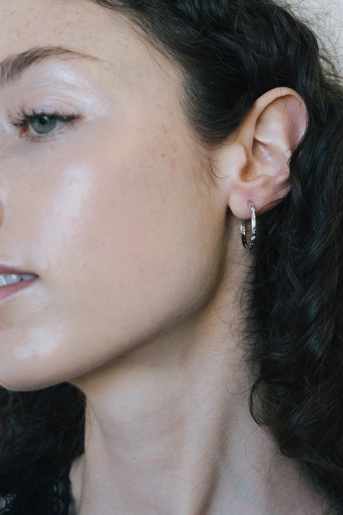 Silver medium hoop earrings with engraved star details and moissanites accents.