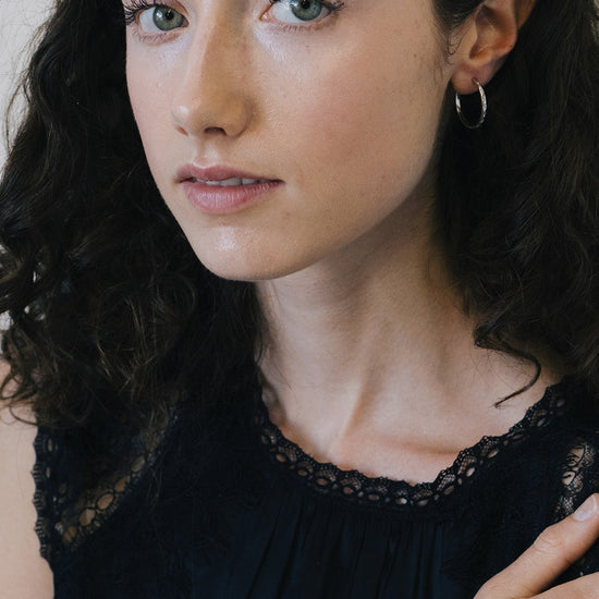 Silver medium hoop earrings with engraved star details and moissanites accents.