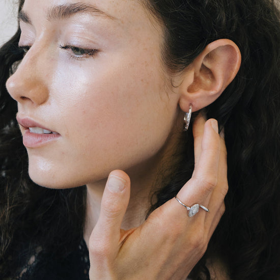 Silver medium hoop earrings with engraved star details and moissanites accents.