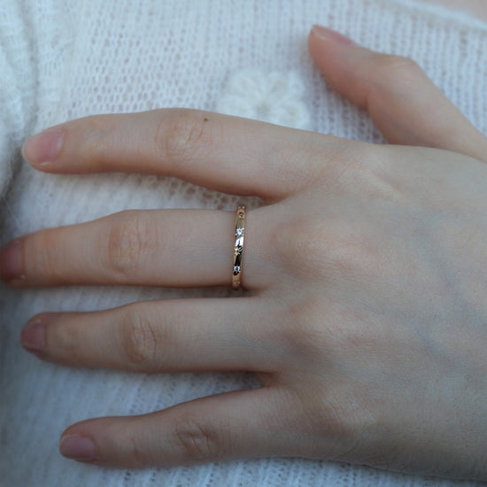 Hand wearing a 14K gold plated ring with starburst engravings, celestial jewelry by Lirae.