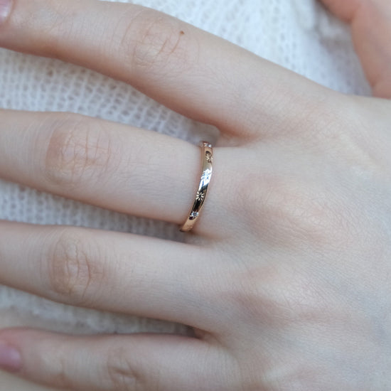 Hand wearing a 14K gold plated ring with starburst engravings, celestial jewelry by Lirae.