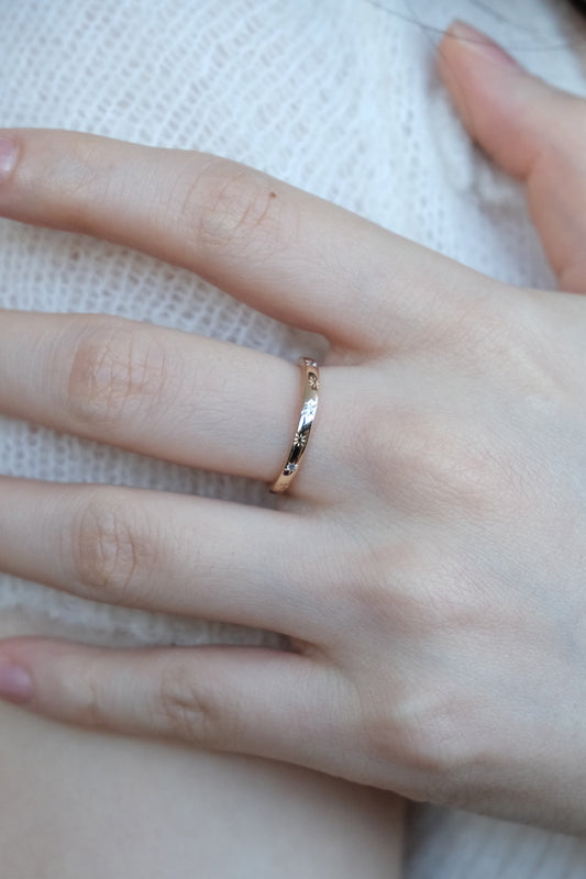 Hand wearing a 14K gold plated ring with starburst engravings, celestial jewelry by Lirae.