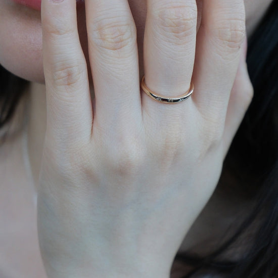 Hand wearing a 14K gold plated ring with starburst engravings, celestial jewelry by Lirae.